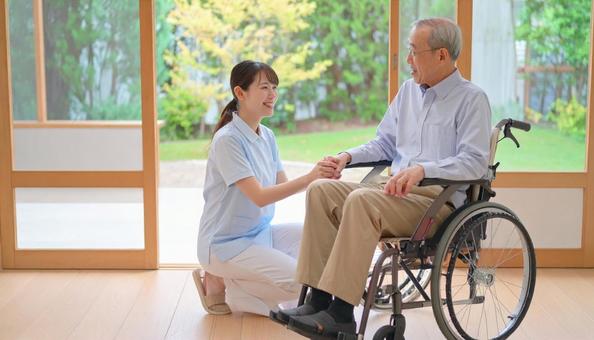 車椅子に乗った高齢男性と女性介護士 車椅子に乗った高齢男性と女性介護士の写真