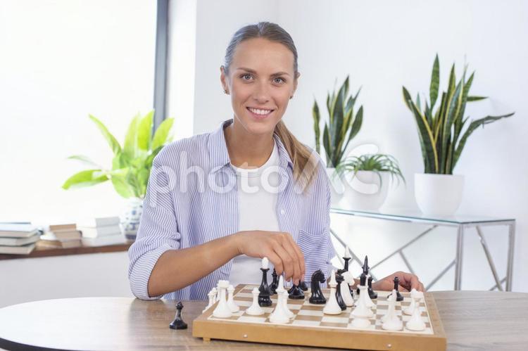 カメラ目線でチェスをする女性 女性,チェス,ボードゲームの写真素材