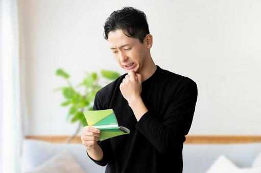 通帳を見て考える男性 通帳を見て考える男性 男性,給料,減給の写真素材
