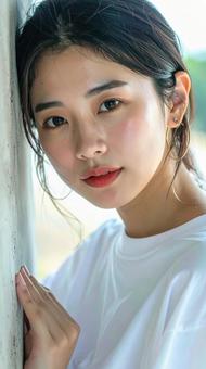 白いTシャツの女性が壁際でポーズをとる 白いTシャツの女性が壁際でポーズをとるの写真