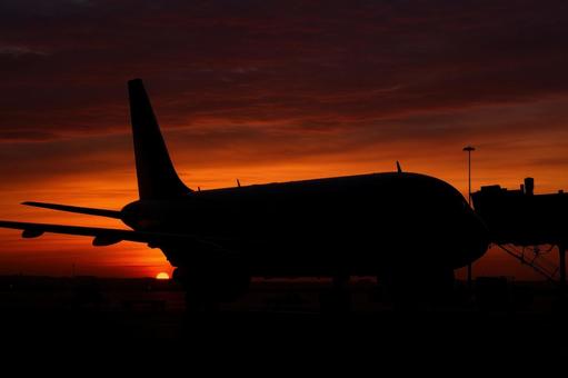 夕暮れの空港にたたずむ機体のシルエットの写真