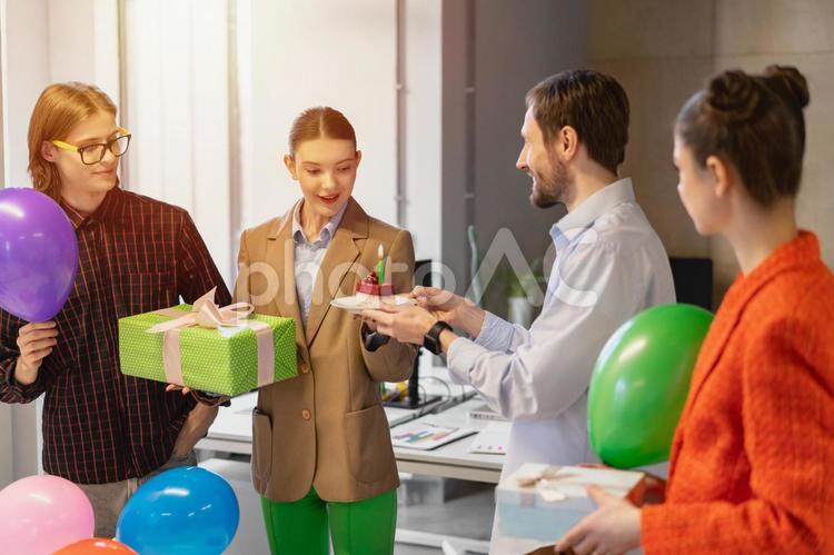 オフィスで女性の誕生日のサプライズをする同僚たち ビジネス,ビジネスマン,ビジネスウーマンの写真素材