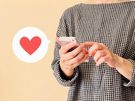 スマホからSNSでいいねする スマホからSNSでいいねする スマホ,女性,ハートの写真素材
