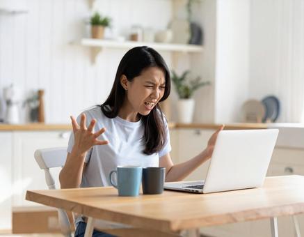 パソコン作業中に怒る女性 パソコン作業中に怒る女性の写真