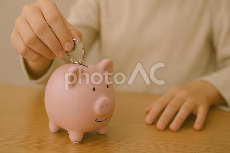 豚の貯金箱に小銭をいれる手元 小銭,小銭貯金,こつこつの写真素材