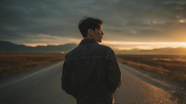 広い荒野の中の道路を歩くGジャンの男性の写真