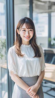オフィスで立つ笑顔の女性会社員 オフィスで立つ笑顔の女性会社員の写真