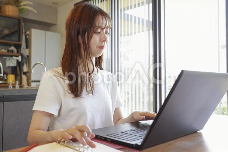 パソコンと手帳を使って仕事をする女性 ノートパソコン,パソコン,pcの写真素材