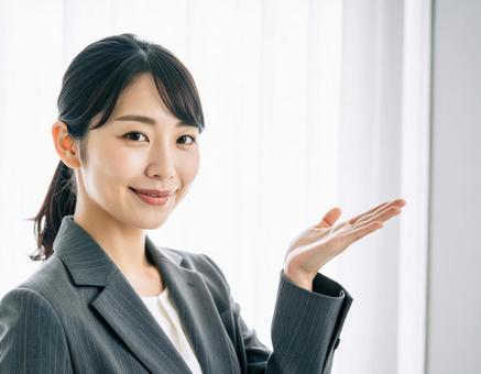 案内ポーズをするスーツ姿の女性 案内ポーズをするスーツ姿の女性の写真