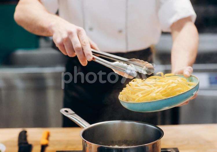 鍋にトングで麺を入れるシェフ キュイジーヌ,キッチン,厨房の写真素材