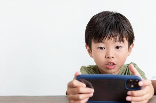 スマホに夢中な男の子 スマホに夢中な男の子の写真