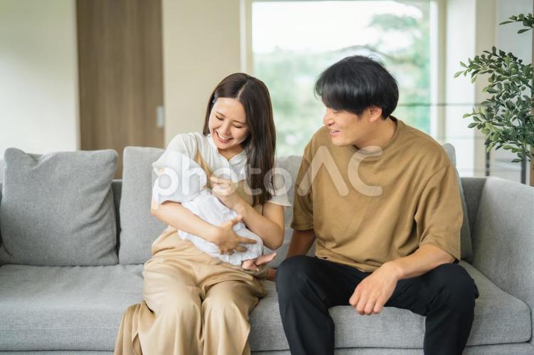 ソファで赤ちゃんを抱く男女 赤ちゃん,育児,新婚の写真素材
