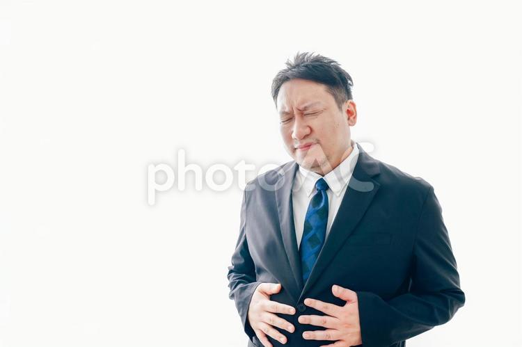 腹痛に苦しむスーツを着た中年男性 吐き気,冷や汗,緊張の写真素材