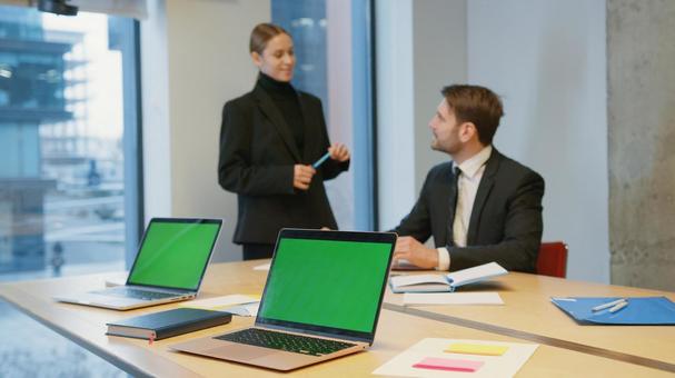 ペンを持ち座っている男性と話している女性 ペンを持ち座っている男性と話している女性の写真