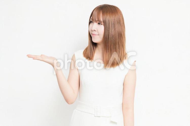 手で案内のジェスチャーをする若い女性 女性,案内,ジェスチャーの写真素材