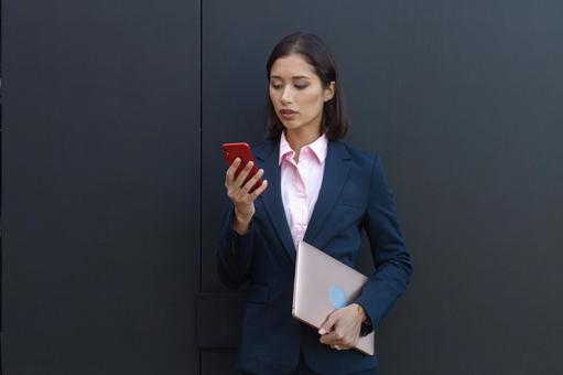 オフィスビルの外でタブレットとスマートフォンを持って立つビジネスウーマン ビジネスウーマン,ビジネス,女性の写真素材