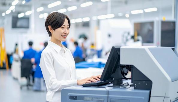 工場の三次元測定機を使う作業服の女性 工場の三次元測定機を使う作業服の女性の写真
