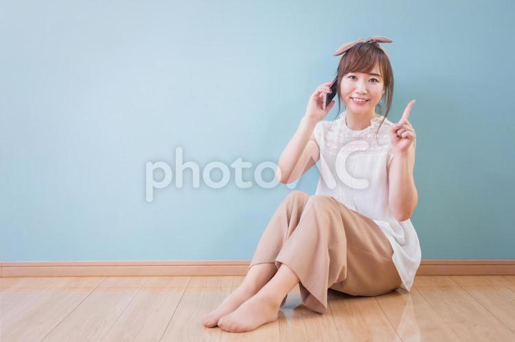 スマホで通話しながら笑顔で指差しをする女性 スマホ,電話,スマートフォンの写真素材