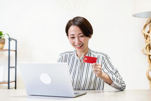 クレジットカードを持ちパソコンを見る女性 オンラインショッピング,クレジットカード,決済の写真素材