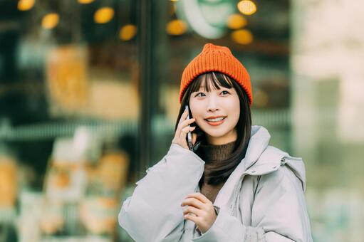 冬の街角でスマホを使う笑顔の女性 冬,女性,街の写真素材