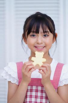 焼き上がったクッキーを手に持つ子どもの笑顔 女の子,クッキー,持つの写真素材