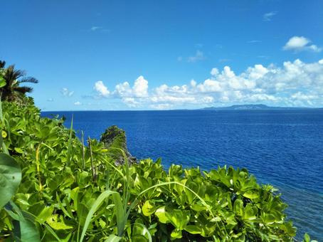 沖縄の青い海と空、緑、雲。の写真