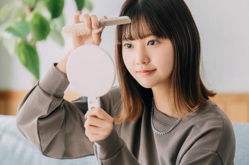 鏡を見ながら髪を整える女性 女性,髪,ブラシの写真素材