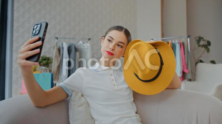 帽子を持ってインカメで撮影する女性 女性,人物,携帯の写真素材