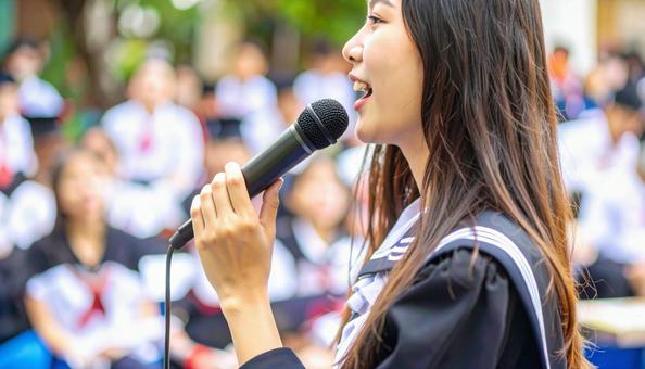 マイクに向かって発表する女子学生の口元 マイクに向かって発表する女子学生の口元の写真
