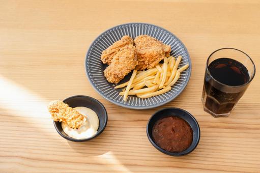 皿に入ったフライドチキンとポテトと烏龍茶 皿に入ったフライドチキンとポテトと烏龍茶の写真