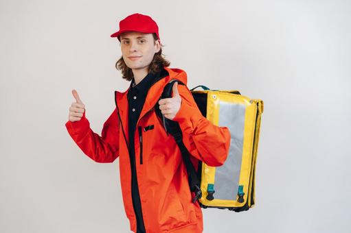 配達バッグを背負ってサムズアップする男性 配達,フードデリバリー,デリバリーの写真素材