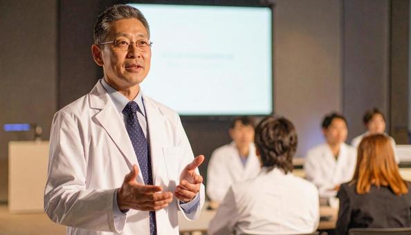 男性医師が壇上で発表、説明をする勉強会 男性医師が壇上で発表、説明をする勉強会の写真