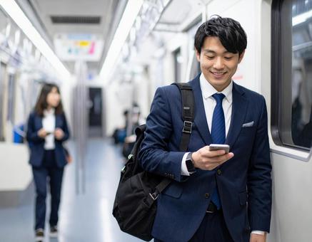 ビジネスシーン・地下鉄出張、スマホを見るの写真