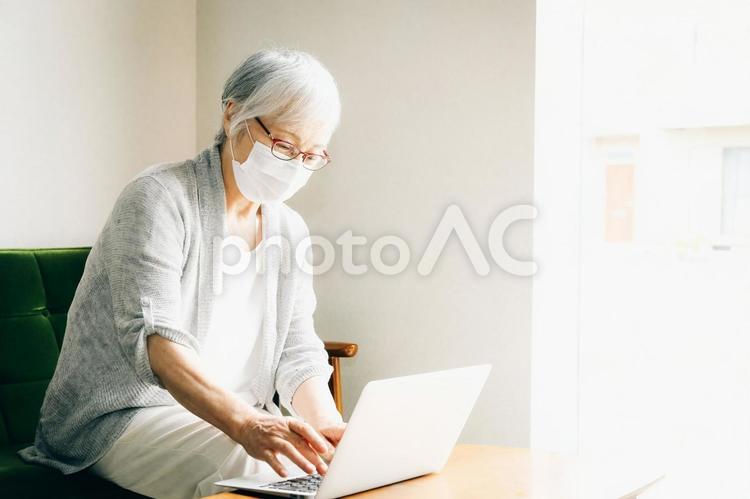 ノートパソコンを使う高齢者女性（マスク姿） ノートパソコン,ビデオ通話,高齢者の写真素材