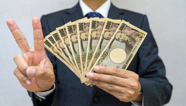 一万円札を持ちピースマークをする男性 一万円札を持ちピースマークをする男性の写真