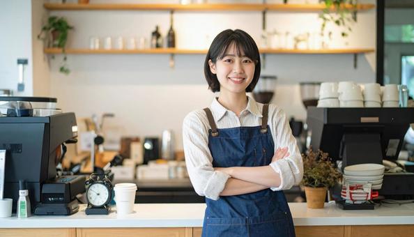 カフェで女性バリスタが笑顔で接客する様子 カフェで女性バリスタが笑顔で接客する様子の写真