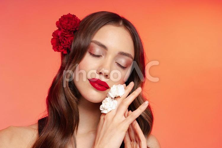 目を瞑り指に白い花を付けた女性 女性,目を瞑る,指を組むの写真素材