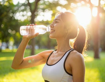 運動後に水を飲むスポーティな女性 運動後に水を飲むスポーティな女性の写真