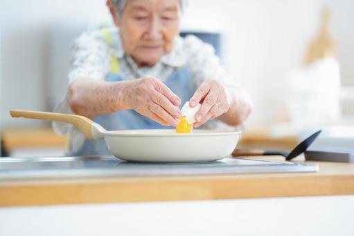 真剣な顔で卵を割る高齢女性 女性,卵,割るの写真素材