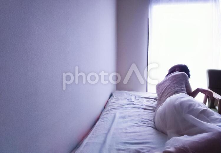 ベッドの上に寝そべる女性(横長) 女性,辛い,ストレスの写真素材