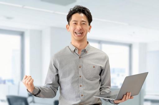 パソコンを持つ笑顔の男性ビジネスマン パソコンを持つ笑顔の男性ビジネスマン 男性,パソコン,ガッツポーズの写真素材