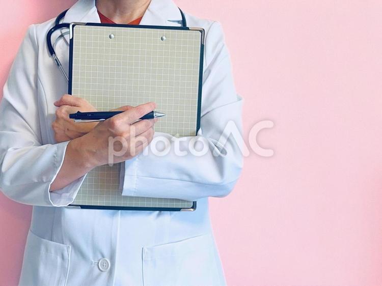 クリップボードを抱えた女医（ピンク背景） 問診票,カルテ,女医の写真素材