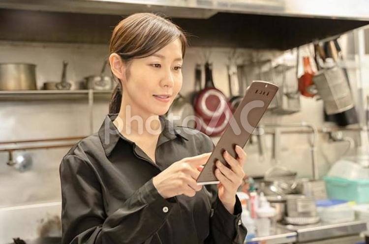飲食店で伝票確認する女性スタッフ 女性,飲食店,仕事の写真素材