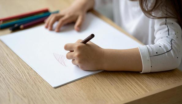 お絵かきをする子供の手もと お絵かきをする子供の手もとの写真