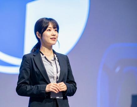 スクリーンの前でプレゼンする女性 スクリーンの前でプレゼンする女性の写真