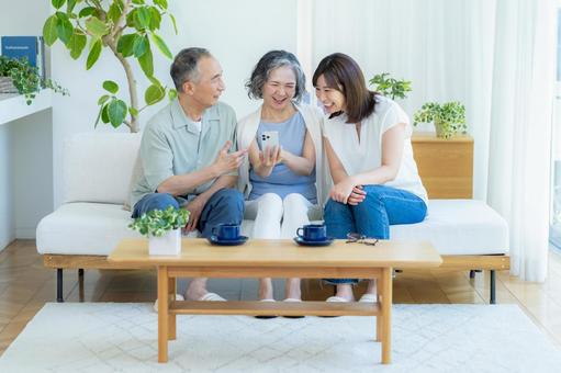 リビングでスマホを見るシニア夫婦と子供 シニア,夫婦,スマホの写真素材
