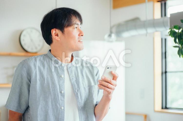 家でスマホを使う男性（アプリ） スマホ,男性,スマートフォンの写真素材