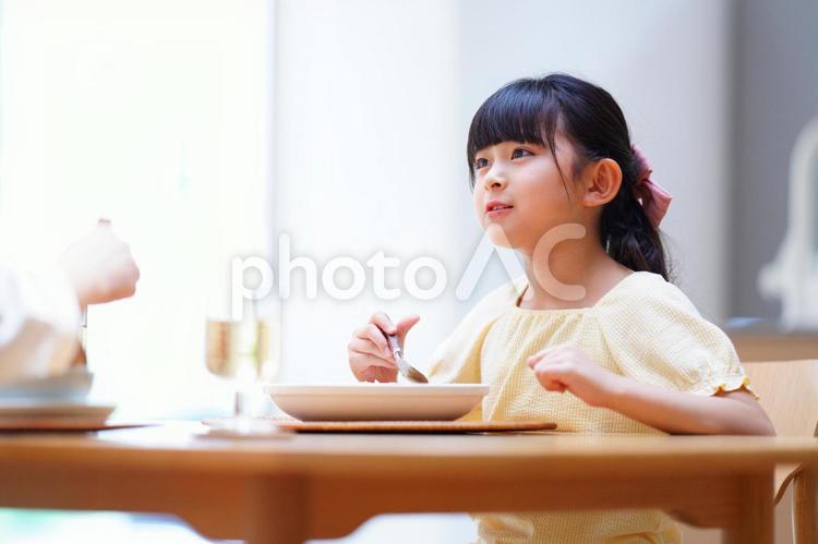 スプーンを持ち話す食事中の女の子 娘,食事,料理の写真素材