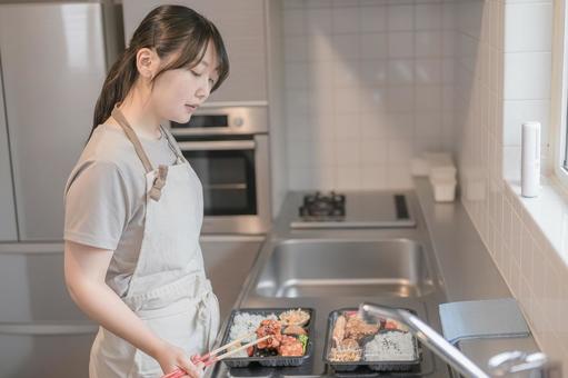 ご飯を詰める女性 ご飯を詰める女性 女性,大人,エプロンの写真素材