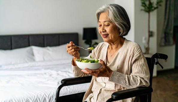 病室で車いすに座り食事をする高齢女性患者 病室で車いすに座り食事をする高齢女性患者の写真